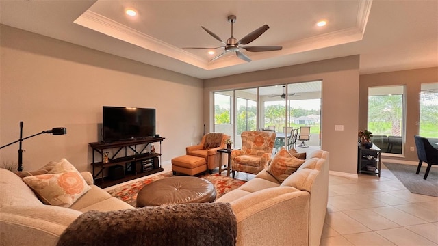 tiled living room with ceiling fan, plenty of natural light, and a raised ceiling