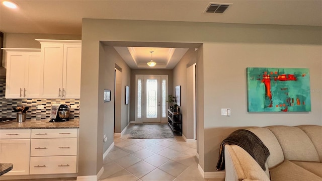 entrance foyer with a tray ceiling and light tile patterned floors