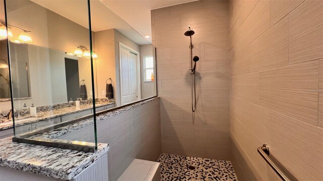 bathroom with tiled shower and vanity