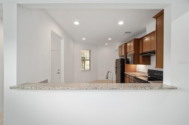 kitchen with black appliances, kitchen peninsula, and light stone counters