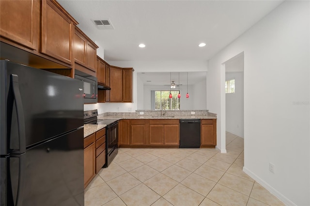 kitchen with light stone counters, exhaust hood, black appliances, decorative light fixtures, and sink