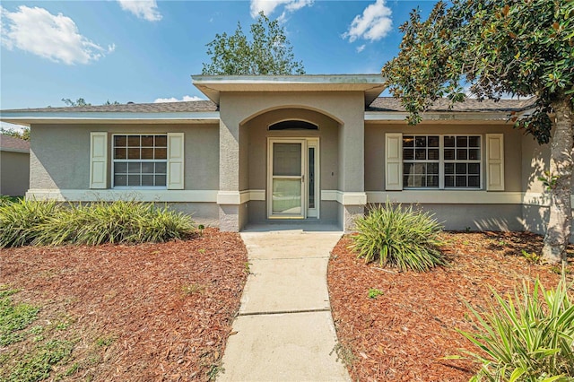 doorway to property with a shingled roof and stucco siding