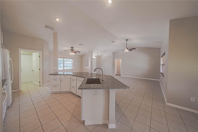 kitchen with light tile patterned floors, vaulted ceiling, white cabinetry, sink, and ceiling fan