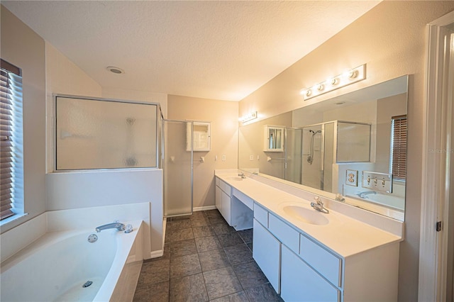 bathroom with vanity, a textured ceiling, a wealth of natural light, and independent shower and bath