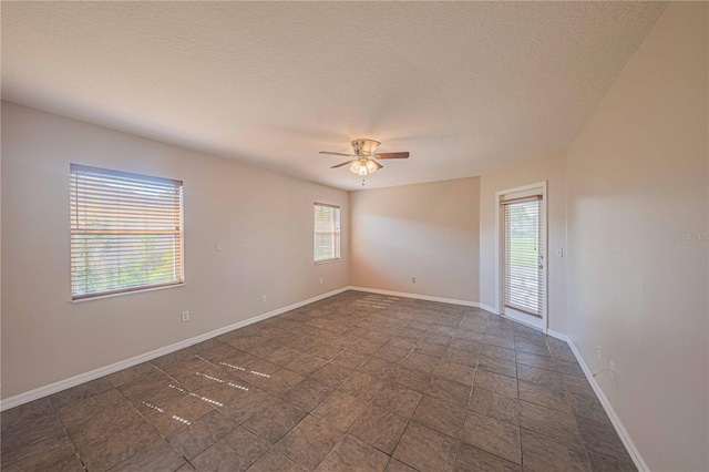 unfurnished room featuring ceiling fan, a textured ceiling, and baseboards