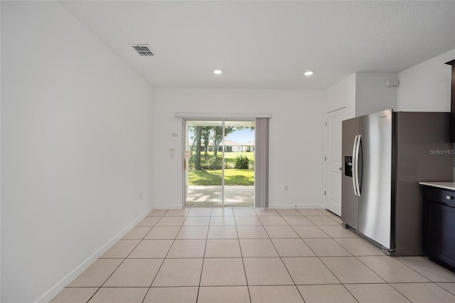 kitchen featuring a textured ceiling, light tile patterned flooring, and stainless steel fridge with ice dispenser