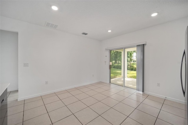 tiled spare room featuring a textured ceiling