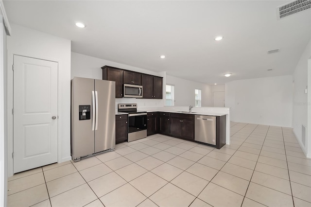 kitchen featuring dark brown cabinetry, light tile patterned flooring, sink, kitchen peninsula, and stainless steel appliances