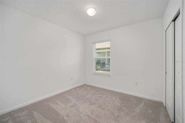 unfurnished bedroom with light carpet and a closet