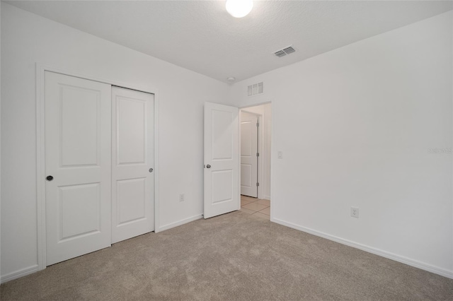 unfurnished bedroom featuring light carpet and a closet