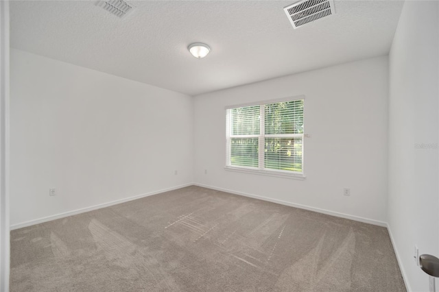 unfurnished room featuring light carpet and a textured ceiling