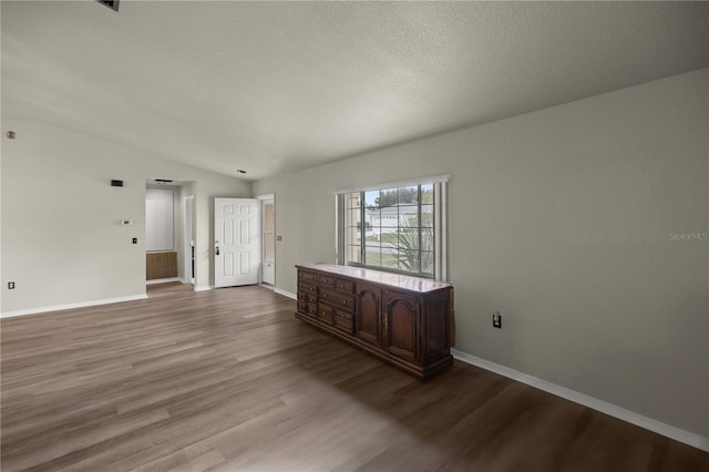 unfurnished room with lofted ceiling, hardwood / wood-style flooring, and a textured ceiling