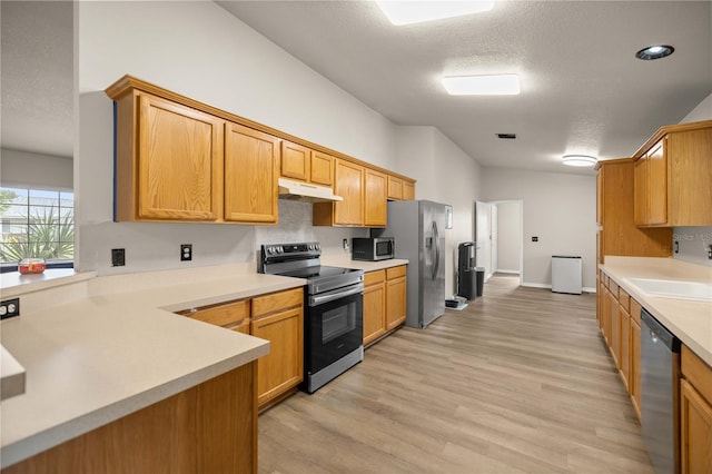 kitchen featuring a textured ceiling, light wood-type flooring, sink, and appliances with stainless steel finishes