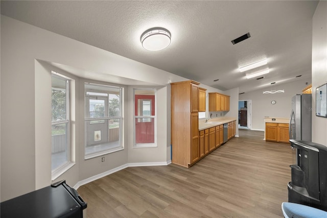 kitchen with light wood-type flooring, a textured ceiling, stainless steel appliances, and sink