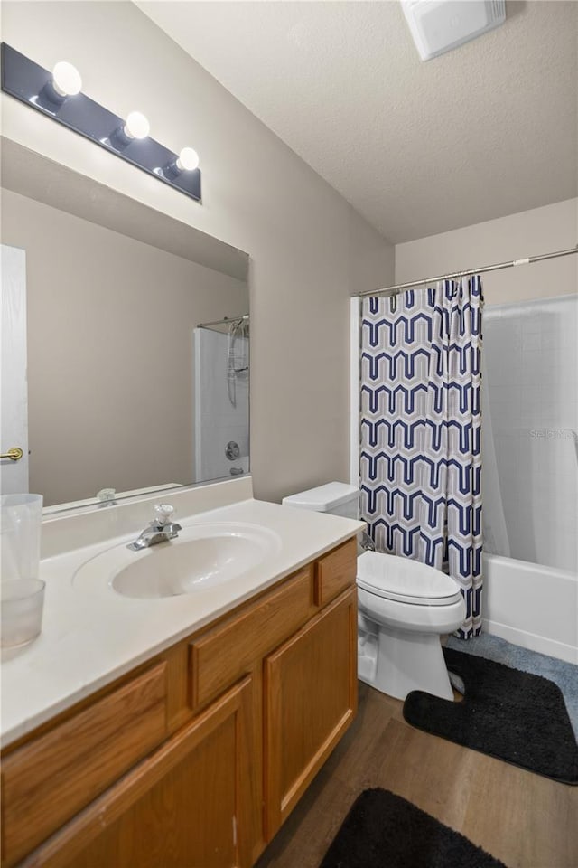 full bathroom featuring toilet, vanity, a textured ceiling, shower / bath combo, and hardwood / wood-style flooring