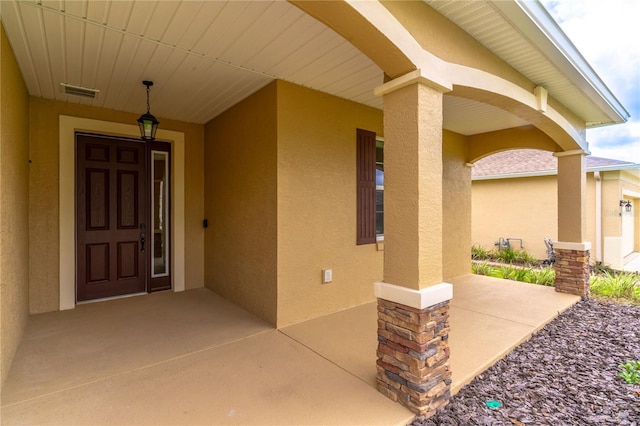 property entrance with visible vents and stucco siding