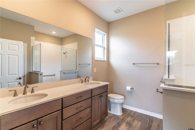 bathroom with wood finished floors, a sink, toilet, and a walk in shower