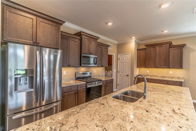 kitchen with ornamental molding, appliances with stainless steel finishes, a sink, and light stone counters