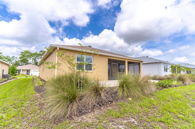 exterior space featuring a lawn, cooling unit, and stucco siding