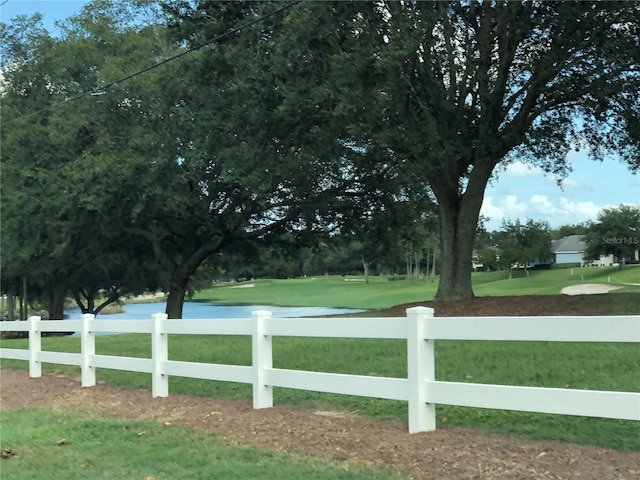 view of community featuring a lawn and fence