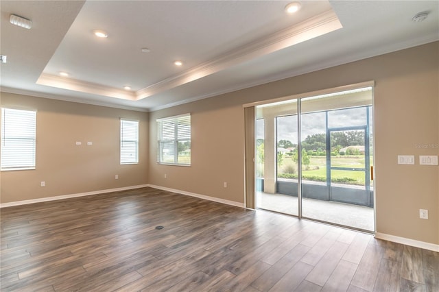 unfurnished room with recessed lighting, baseboards, ornamental molding, dark wood-style floors, and a raised ceiling