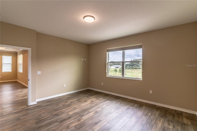 empty room with baseboards, dark wood finished floors, and a textured ceiling