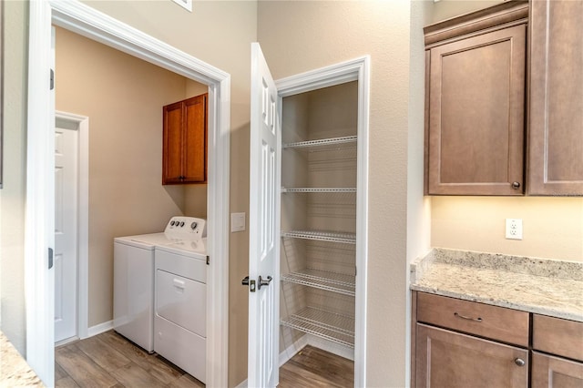 laundry room featuring light wood-style flooring, cabinet space, washer and clothes dryer, and baseboards