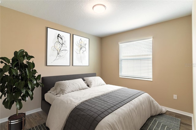 bedroom featuring a textured ceiling, baseboards, and wood finished floors