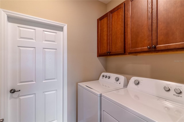 clothes washing area featuring cabinet space and washer and clothes dryer