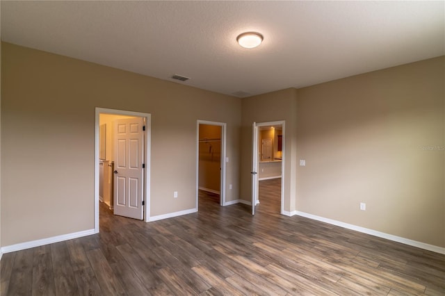 9994 SW 96th St, Ocala, FL 34481 - unfurnished bedroom with a closet, baseboards, a walk in closet, dark wood-type flooring, and visible vents
