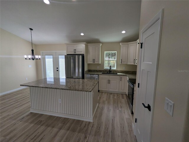 kitchen with white cabinetry, sink, stainless steel appliances, a kitchen island, and light wood-type flooring