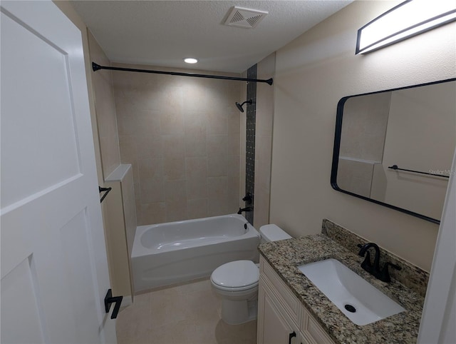 full bathroom with vanity, tile patterned floors, tiled shower / bath, toilet, and a textured ceiling