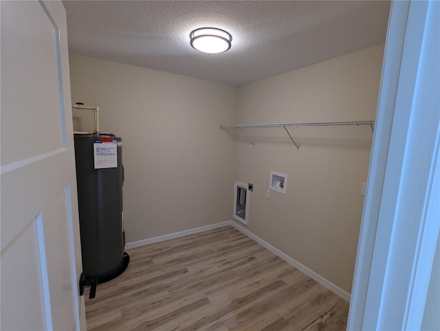 laundry room featuring hookup for an electric dryer, washer hookup, a textured ceiling, water heater, and light hardwood / wood-style flooring