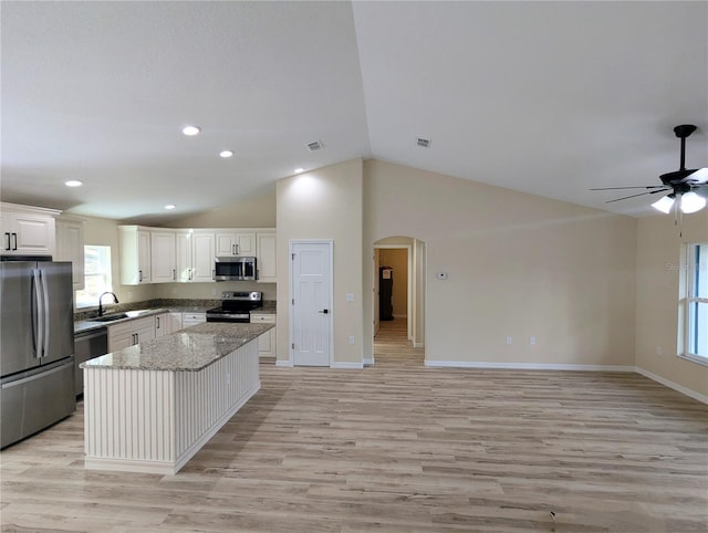 kitchen featuring light stone countertops, stainless steel appliances, white cabinetry, light hardwood / wood-style floors, and a kitchen island