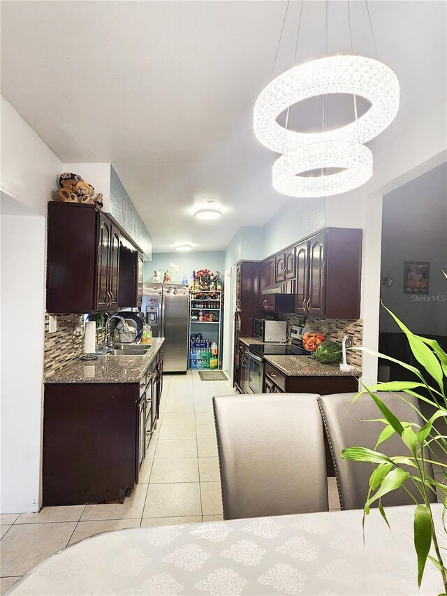 kitchen with dark brown cabinets, light tile patterned floors, sink, decorative backsplash, and appliances with stainless steel finishes