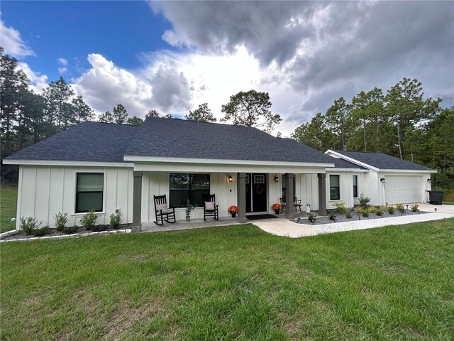 single story home featuring a front yard, a porch, and a garage