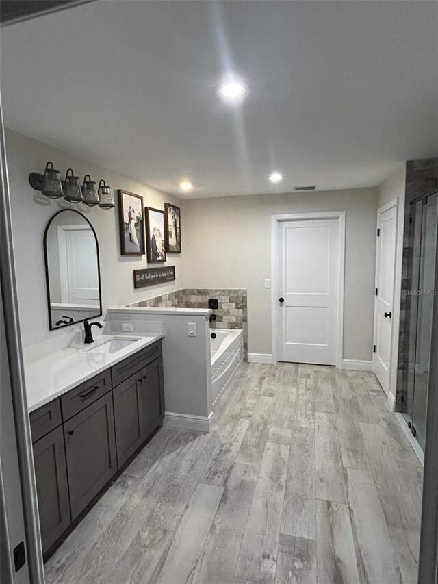 bathroom featuring wood-type flooring, independent shower and bath, and vanity