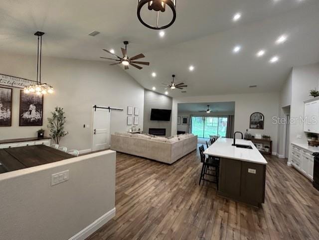 kitchen with white cabinetry, a barn door, dark hardwood / wood-style flooring, ceiling fan, and a kitchen island with sink