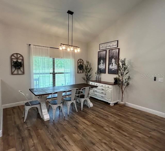 dining space featuring dark hardwood / wood-style floors and vaulted ceiling