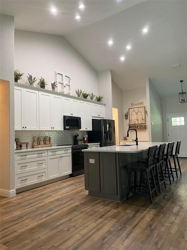 kitchen featuring a large island, dark wood-type flooring, white cabinetry, and black appliances