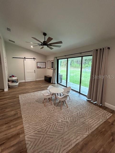 unfurnished living room with a barn door, vaulted ceiling, ceiling fan, and hardwood / wood-style flooring