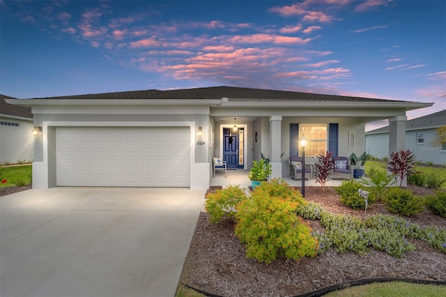 ranch-style house with an attached garage, covered porch, driveway, and stucco siding