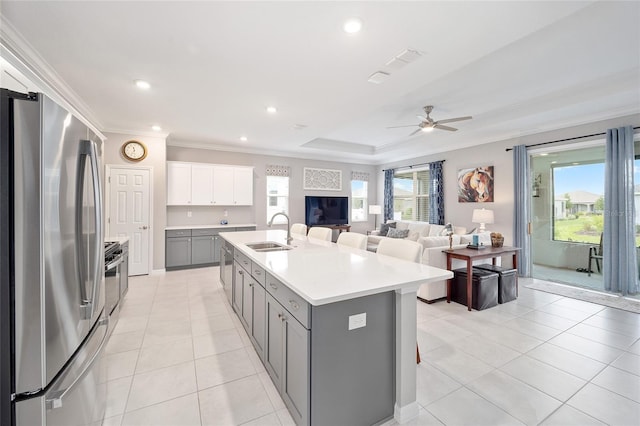 kitchen with light tile patterned floors, ornamental molding, gray cabinets, stainless steel appliances, and a sink