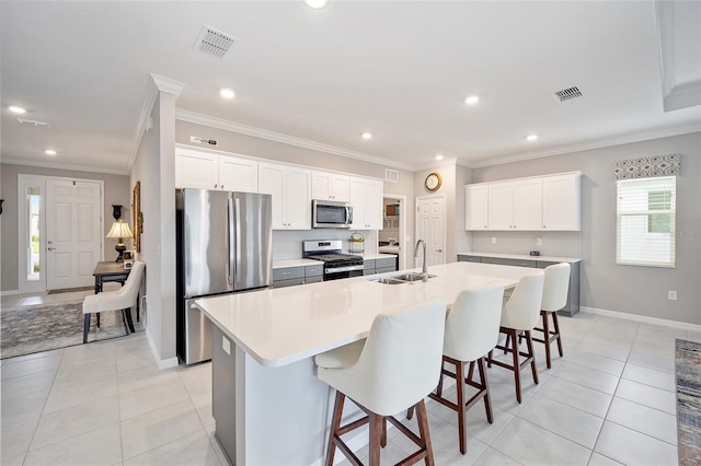 kitchen featuring appliances with stainless steel finishes, a large island with sink, visible vents, and a sink