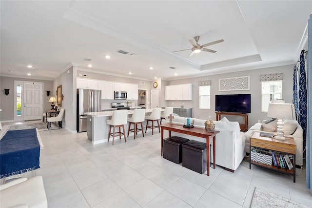 living room featuring ornamental molding, a raised ceiling, and a wealth of natural light