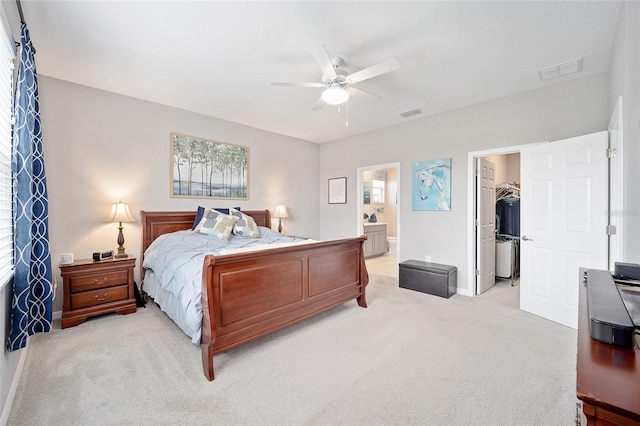 bedroom with a spacious closet, ensuite bath, visible vents, and light colored carpet