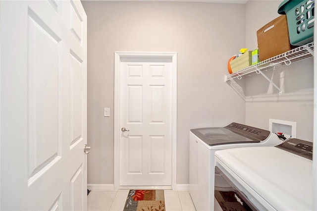 washroom with laundry area, washer and clothes dryer, baseboards, and light tile patterned floors