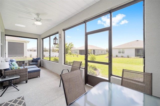 sunroom / solarium featuring a residential view and a ceiling fan