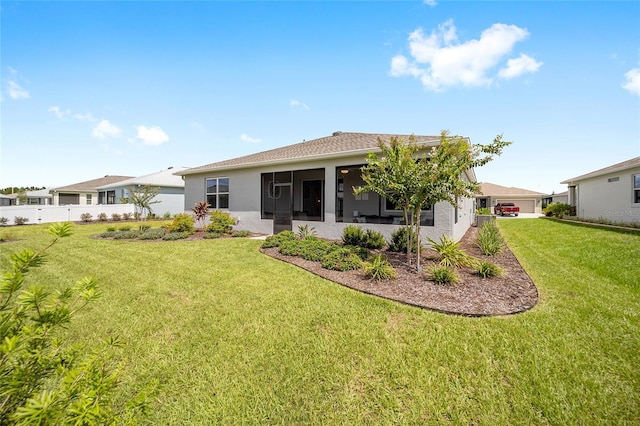 back of property featuring a sunroom, a lawn, fence, and stucco siding