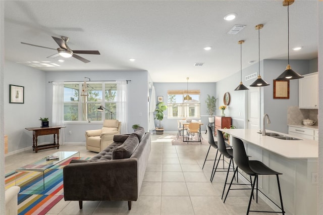 tiled living room featuring ceiling fan, sink, and a textured ceiling